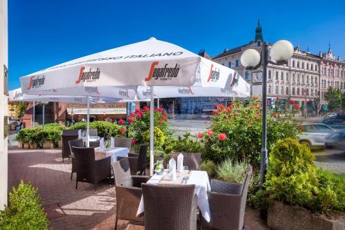 a restaurant with tables and chairs under an umbrella at Hotel Trinity in Olomouc