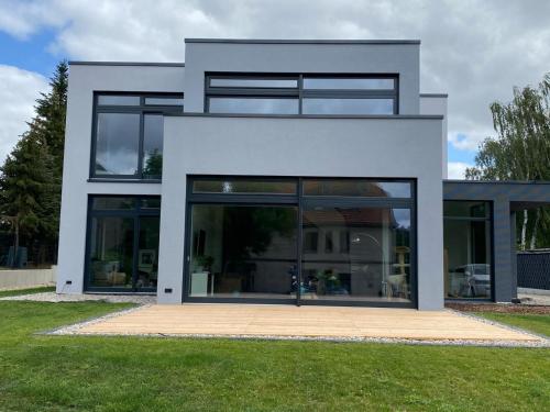 a white house with large glass windows at helle Ferienwohnung in Architektenhaus mit Garten und Pool in Bad Belzig