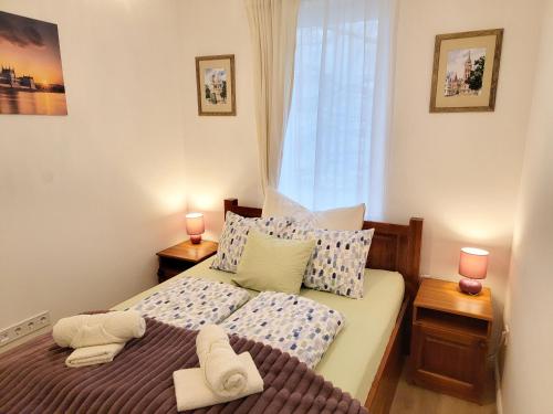 a bedroom with a bed with two lamps and a window at Moonshine Érd in Érd