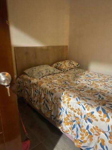 een bed in een slaapkamer met een sprei met bloemen erop bij Departamento centrico in Ilo