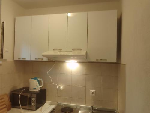 una cocina con armarios blancos y una luz en la encimera en Apartment Luka, en Trogir
