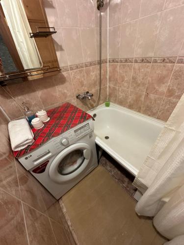 uma casa de banho com uma máquina de lavar roupa e uma banheira em Квартира по Республике 16/2 em Karaganda