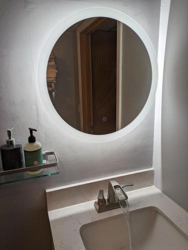 a bathroom with a sink with a round mirror at ECLIPSE Vermont in Colchester