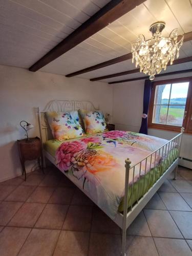 a bedroom with a bed with colorful pillows and a chandelier at LilaLila Lodge in Magdenau