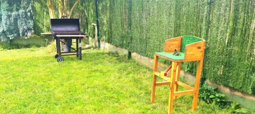 einen Grill und einen Holztisch und einen Stuhl im Gras in der Unterkunft Bonito bajo con jardín in Bárcena de Cicero