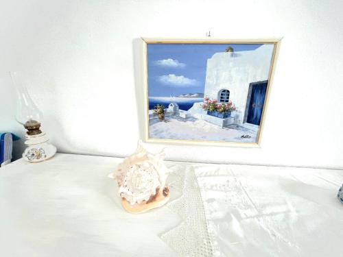 a picture of a painting on a wall with a table at Oia Sunset House Pothitou in Oia