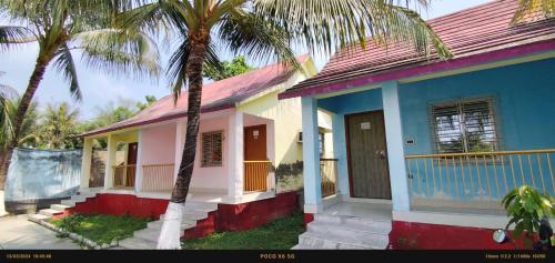 a house with two palm trees in front of it at India Tours only Ekanta Apan in Mathurakhanga