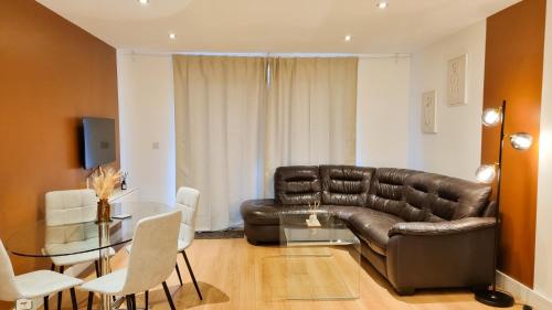 a living room with a leather couch and a table at Stunning Ground Floor Apartment for Business & Leisure Stays in RG2 - Sleeps up to 6! in Reading