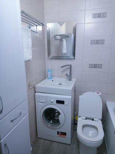 a small bathroom with a washing machine and a toilet at Уют в сердце Алматы in Almaty