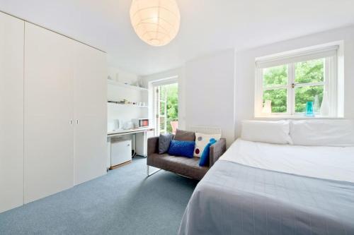 a white bedroom with a bed and a chair at Zone 1! 2 bed duplex Apartment! in London