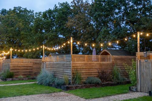 a fence with string lights and a garden at Woodlakes Park By Liv Retreats in Kings Lynn