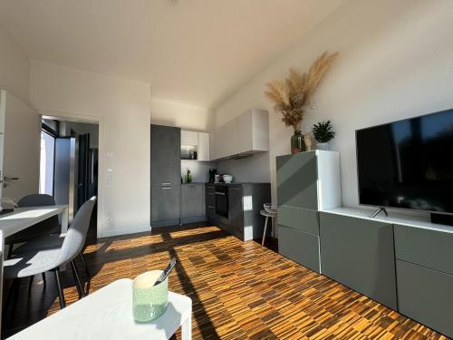 a living room with a large television and a kitchen at helle Ferienwohnung in Architektenhaus mit Garten und Pool in Bad Belzig