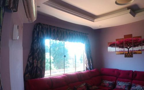 um sofá vermelho numa sala de estar com uma janela em Ñande renda em Ciudad del Este