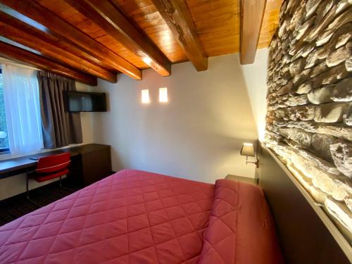 a bedroom with a pink bed and a stone wall at Gemelli Hotel in Rome