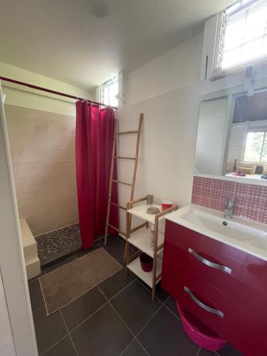 uma casa de banho com uma cortina de chuveiro vermelha e um lavatório. em Eden Créole em Trois-Rivières