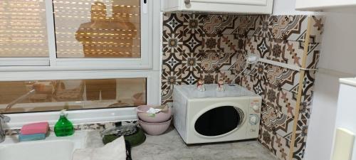 un microondas sentado junto a un fregadero en la cocina en IMMEUBLE BRINI en Kairouan