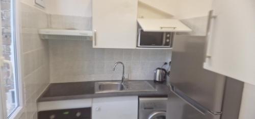 une petite cuisine avec un évier et un micro-ondes dans l'établissement Appartement T2 porte la défense, à Colombes
