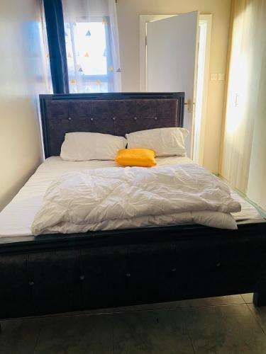 a bed with an orange blanket and pillows on it at Tsavo Studios Apartment in Nairobi