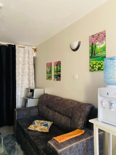 a living room with a large brown couch and a window at Tsavo Studios Apartment in Nairobi