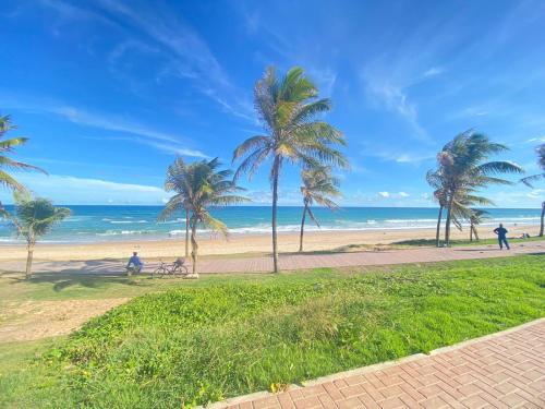 a beach with palm trees and people walking on a sidewalk at Quarto em stella maris in Salvador