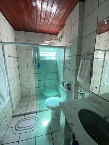 a bathroom with a toilet and a shower and a sink at Quarto em stella maris in Salvador