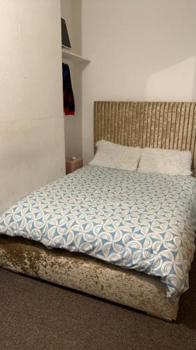 a bedroom with a bed with a blue and white comforter at 68 Halsbury Road in Liverpool