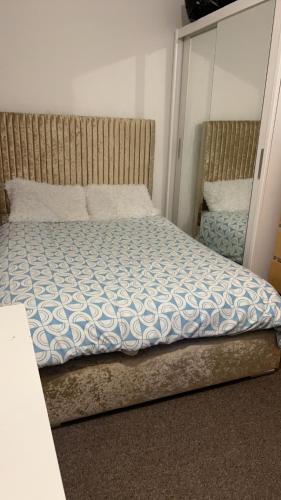 um quarto com uma cama com um edredão azul e branco em 68 Halsbury Road em Liverpool