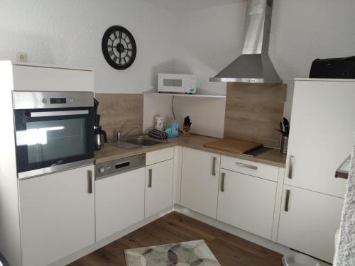 a kitchen with white cabinets and a clock on the wall at Bungalow 269 in Tossens in Tossenserdeich