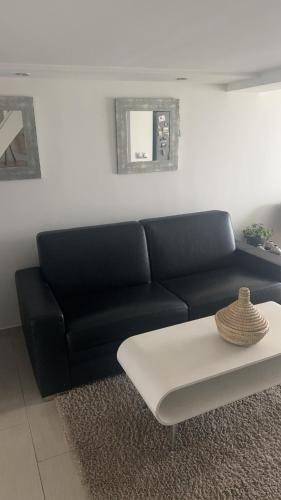 sala de estar con sofá negro y mesa de centro blanca en Lamajorelle, en Deuil-la-Barre