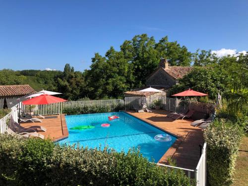 a swimming pool with chairs and umbrellas in a yard at Les Coquilles Pourpres in Lolme