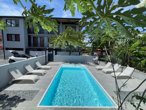 a swimming pool with chairs and a house at Le refuge rafraîchissant in Montjoly