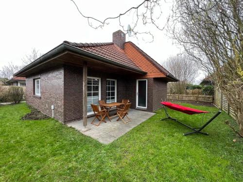 a small brick house with a picnic table and a red bench at Bungalow 269 in Tossens in Tossenserdeich