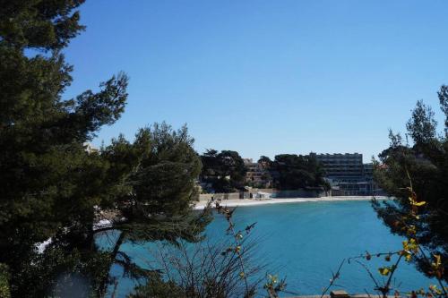 une grande piscine avec une plage et un bâtiment dans l'établissement Havre de paix Provencal, à Bandol