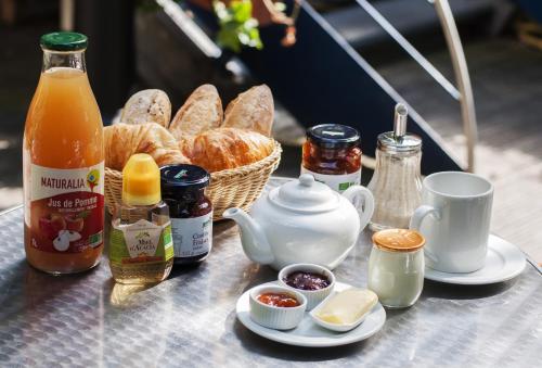a table with a tea kettle and a basket of bread at Solar Hotel in Paris