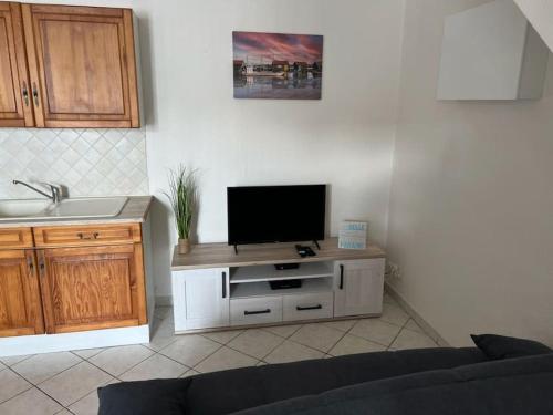 a living room with a flat screen tv on a cabinet at Appartement à deux pas du Port in La Tremblade
