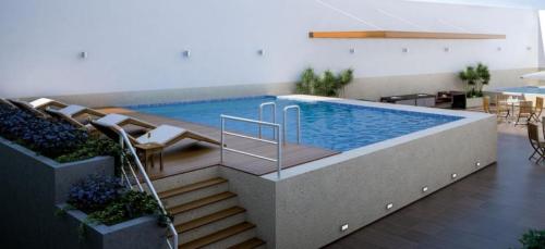 una piscina en un edificio con sillas y mesas en Hermoso apartamento Unidos En Familia en JESÚS MARÍA, en Lima