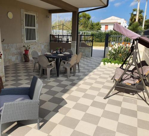 a patio with a table and chairs on a checkered floor at Villa Tellina Mare Luna in Granelli