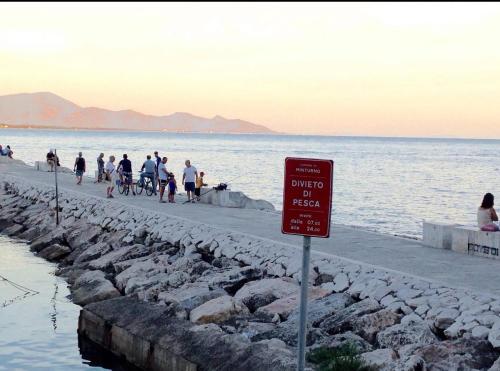 a group of people walking on a pier next to the water at Villa Lidia & Attico degli artisti, free pets , giardino recintato e attrezzato in Minturno