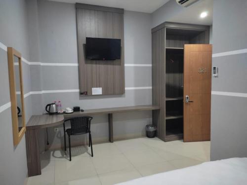a room with a desk and a tv on a wall at BahuBay Hotel Manado in Malalayang