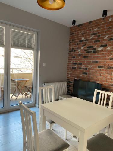 comedor con mesa, sillas y pared de ladrillo en Apartament Centrum Więckowskiego, en Łódź