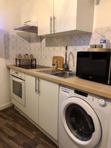 uma cozinha com uma máquina de lavar roupa e um lavatório em Studio lumineux et équipé em Villemomble