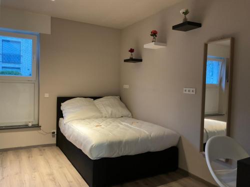 a bedroom with a bed with white sheets and a window at Modernes Studio am Dreiländereck in Alsdorf