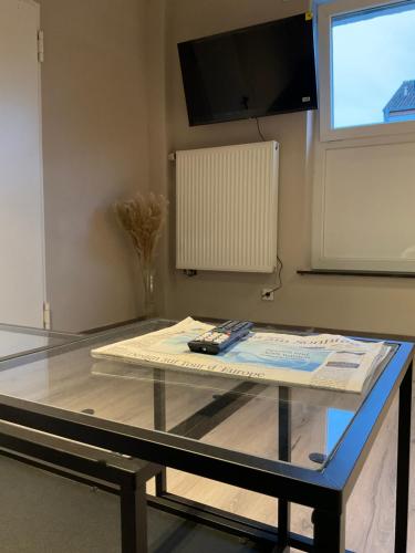 a glass table in a room with a tv at Modernes Studio am Dreiländereck in Alsdorf