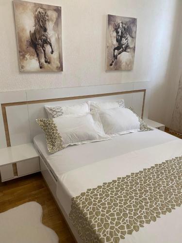 a bed in a bedroom with two paintings on the wall at Апартамент “Djanina 2” in Sandanski