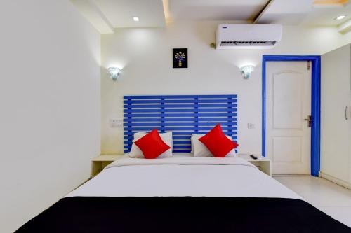 een slaapkamer met een wit bed met rode kussens bij Collection O CORACAO HOTEL in Jaipur