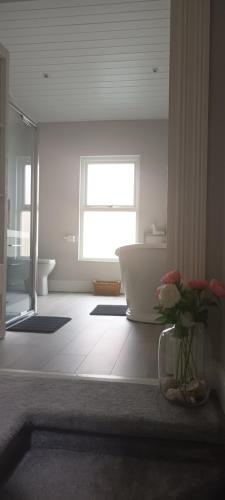 a bathroom with a tub and a vase of flowers at Eglinton Road - Super King - Private Bathroom in Bray