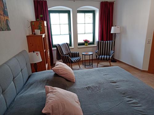 a bedroom with a bed and chairs and windows at Apartment Am Markt 4 in Bad Gottleuba