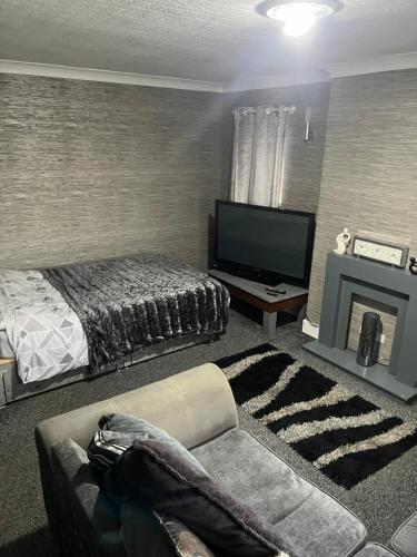 1 dormitorio con 1 cama, TV y sofá en Charlies, en Skegness