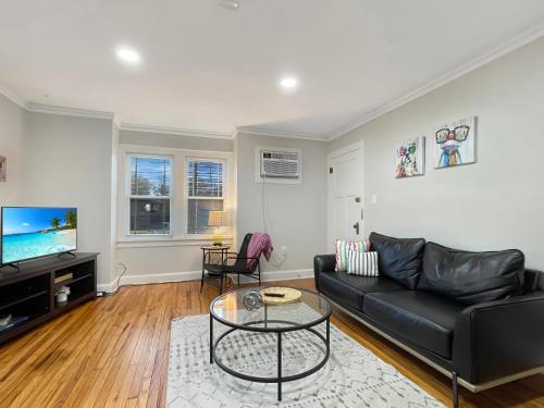 a living room with a black couch and a tv at Fun & Charming 1br Apt Near Drake in Des Moines