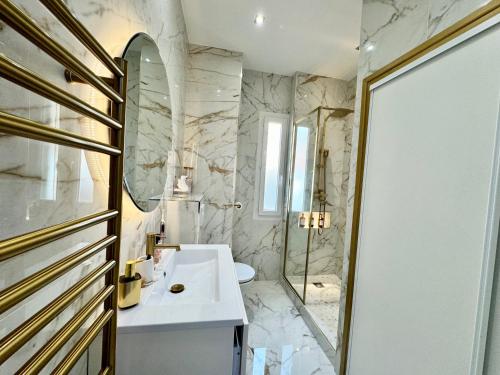 ein Badezimmer mit einem weißen Waschbecken und einem Spiegel in der Unterkunft Appartement vue mer vue Monaco in Beausoleil